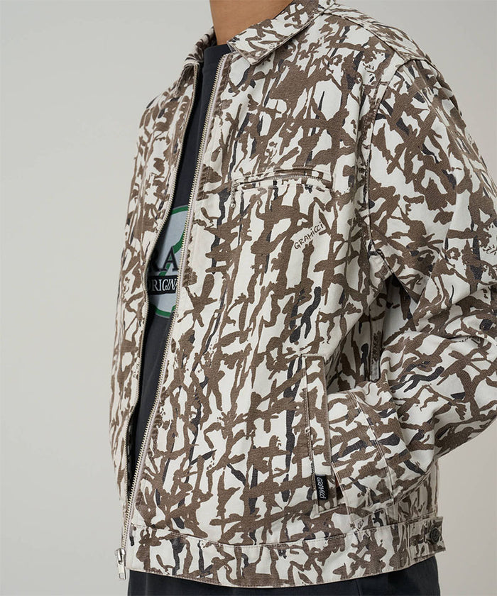 Model wearing a Gramicci grey reed camouflage Taos Canvas Jacket against a light-tone background.