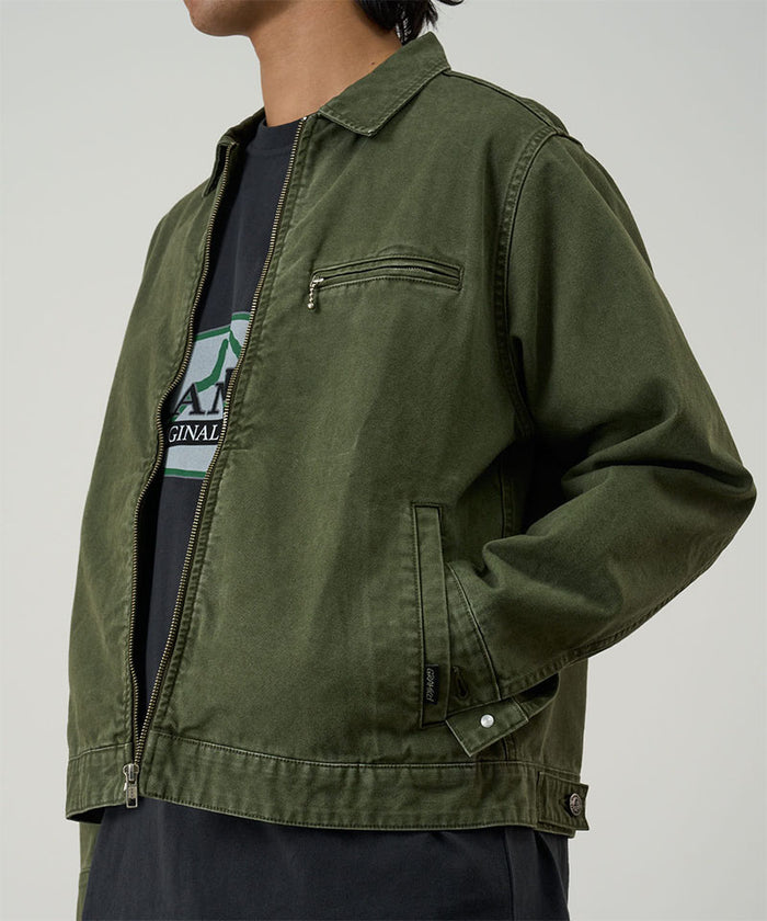 Model wearing a Gramicci moss green Taos Canvas Jacket against a light-tone background.