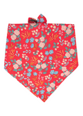A cheerful red dog bandana adorned with an all-over floral pattern of soft blooms, and leaves, tied at the top in a classic triangle shape for a fun, fashionable flair.