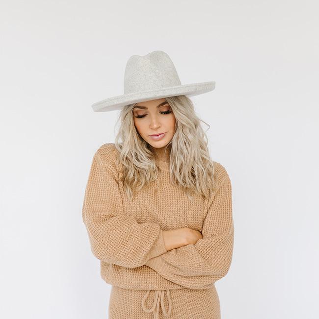 Woman wearing a heather grey colored pencil brim hat and a brown sweater and brown pants against a plain background #color_heather grey