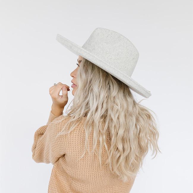 Woman wearing a heather grey colored pencil brim hat and a brown sweater, looking sideways against a plain background #color_heather grey