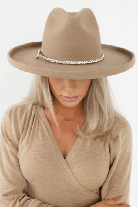 Woman wearing a tan pencil brim felt hat with a hat band and a beige shirt against a plain background #color_tan