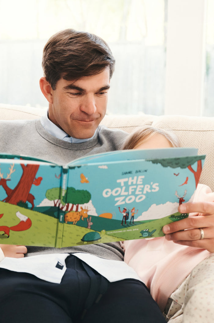 Man with his daughter reading The Golfer's Zoo Book