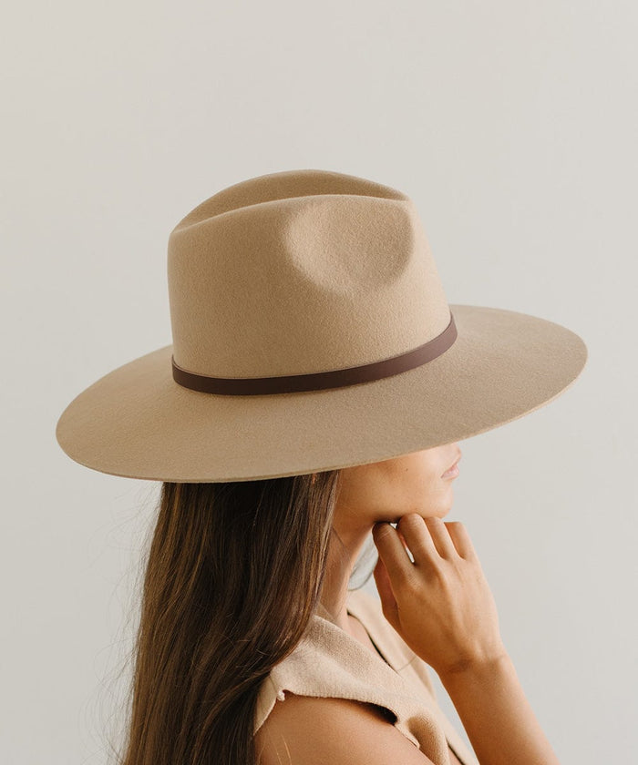 Woman wearing a beige felt hat with a thin chocolate colored leather hat band around the base, facing sideways against a plain background  #color_chocolate
