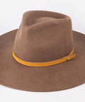 A brown felt wide-brim hat with a contrasting mustard yellow leather band and a small gold-tone metal stud, shown on a plain white background #color_cognac