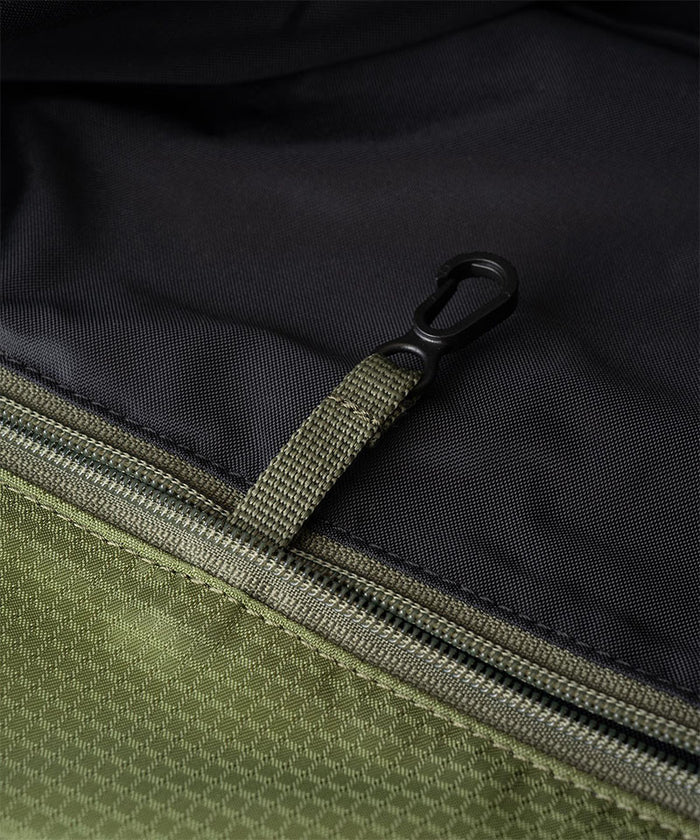 Close-up of Gramicci Tote Pack bag in the color olive with black interior against a light-tone background.