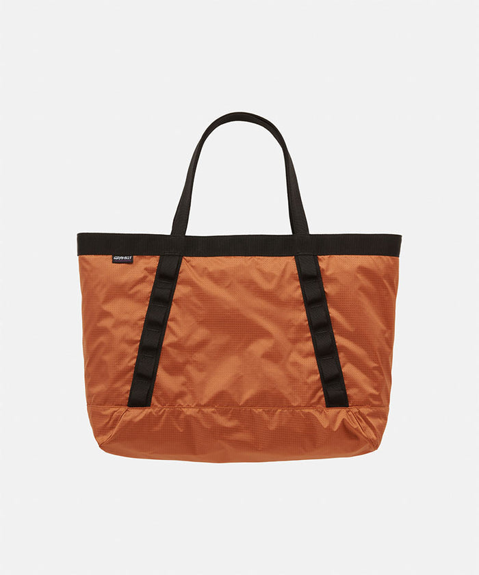 Orange Gramicci Trail Tote bag with black straps on a light tone background
