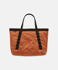 Orange Gramicci Trail Tote bag with black straps on a light tone background