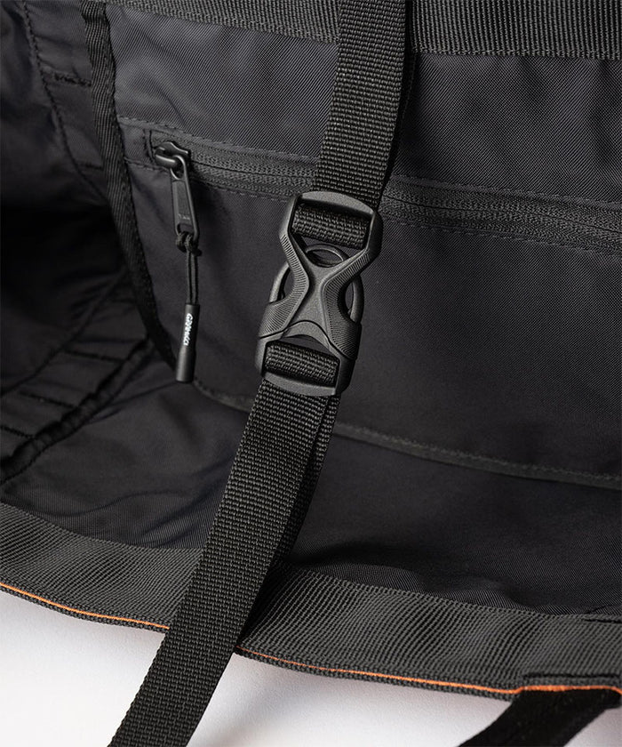 Inside view of an orange Gramicci Trail Tote bag with a black interior and black strap with a buckle on a light tone background.