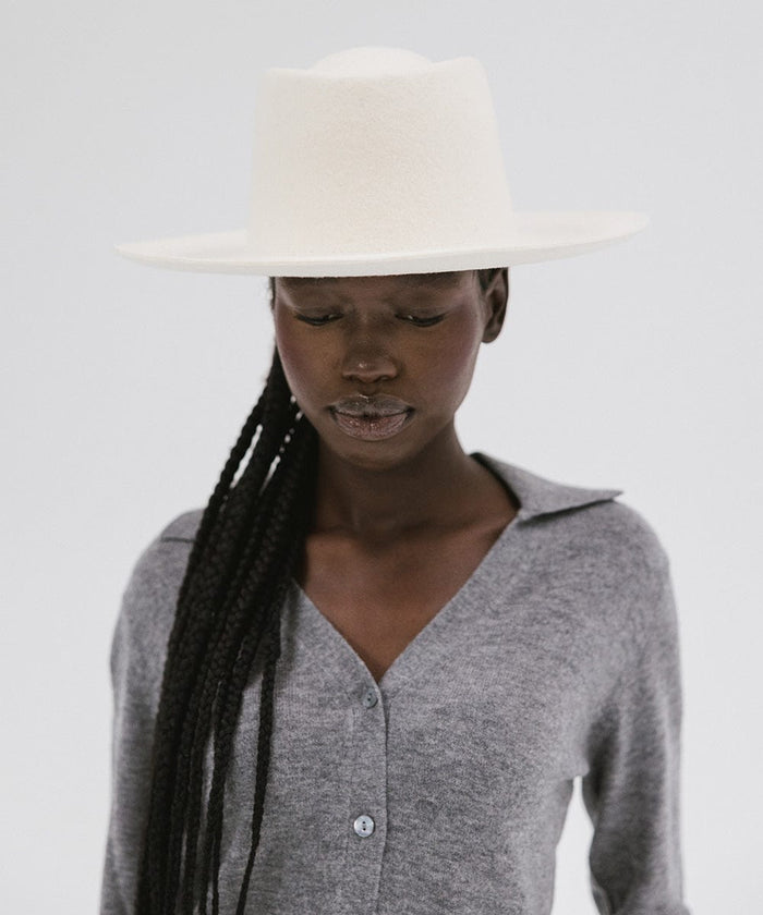 Woman wearing an off white gambler hat and a grey shirt against a plain background #color_off white