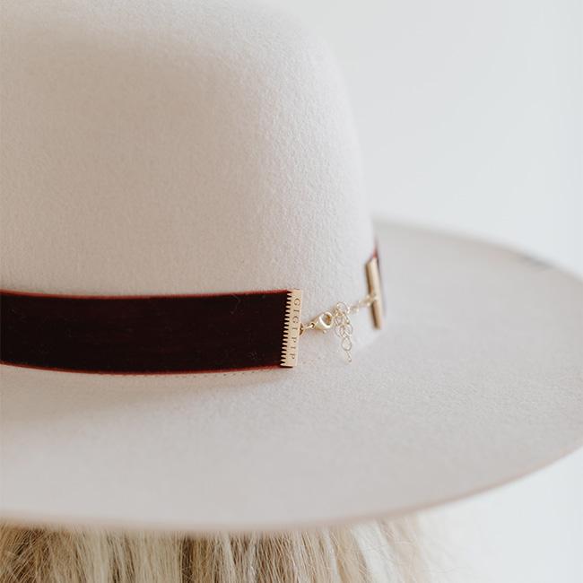Close up image of a white hat with a rusty red velvet chain hat band against a plain background #color_rusty red