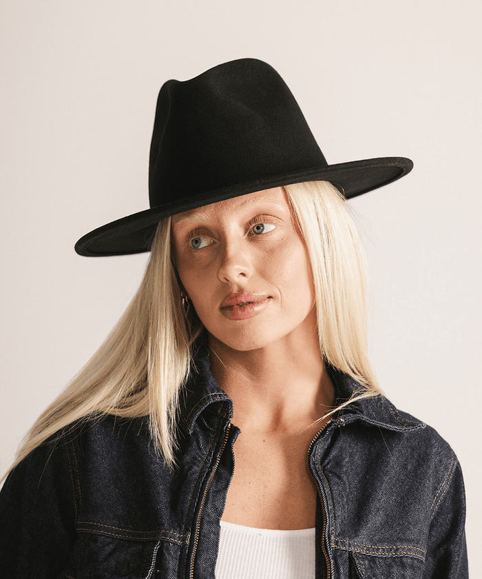 Woman wearing a black fedora hat against a plain background #color_black