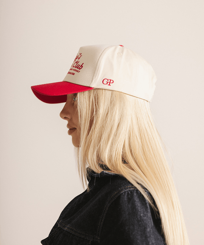Person wearing a beige and red cap with visible branding on a plain background #color_cream - red