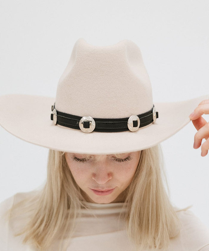 A woman wearing a white hat with a black western style genuine leather hat band against a plain background #color_black