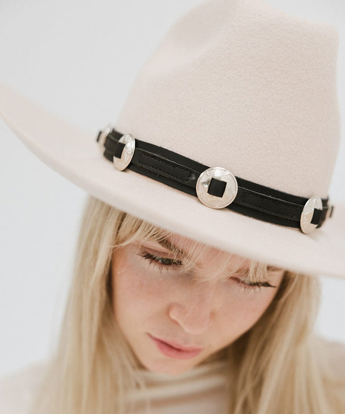 Close up image of a woman wearing a white hat with a black western style genuine leather hat band against a plain background #color_black