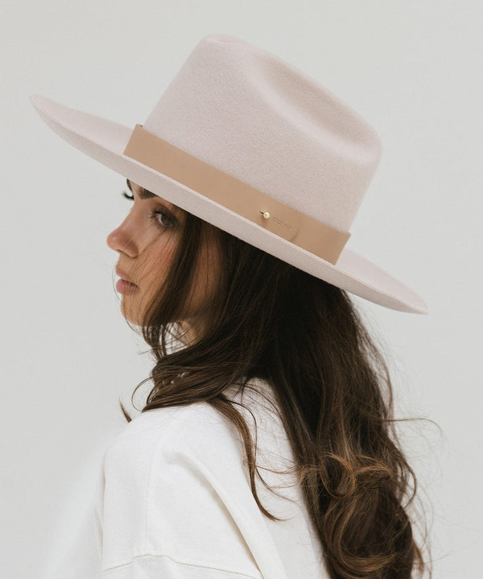 Woman wearing a cream hat with a wide tan leather band around the base, posing sideways against a plain background  #color_tan