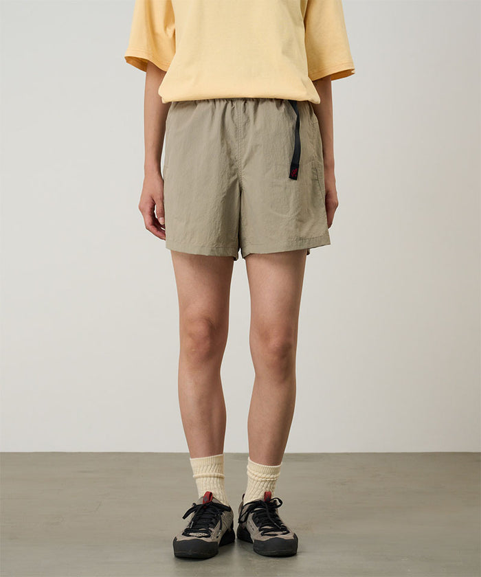 Model wearing milk tea Gramicci Women's Nylon Active Short and a yellow shirt on a light-tone background.