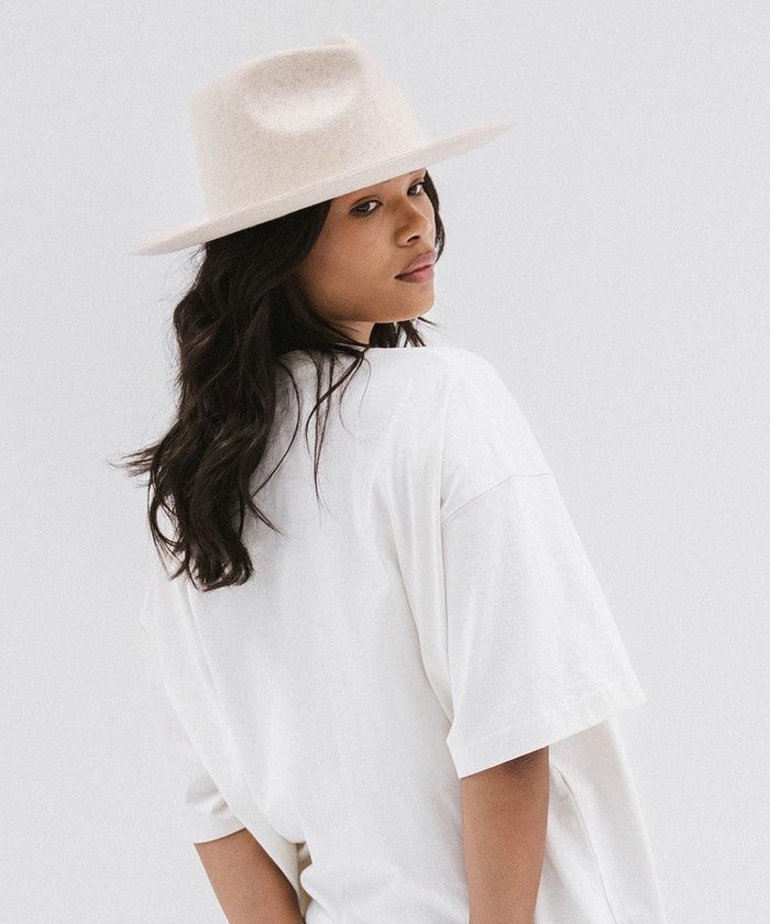 Woman wearing a mix ivory colored fedora hat and a white shirt, posing against a white background #color_mix ivory